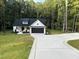 White farmhouse exterior with black garage door and landscaping at 114 Shaman Dr, Louisburg, NC 27549