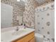 Bathroom with floral wallpaper, a single vanity, and shower/tub combo at 107 Knottingham Ct, Dunn, NC 28334