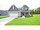 Two-story home with gray siding, stone accents, and a white two-car garage at 236 Abingdon Farms Dr, Selma, NC 27576