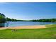 Peaceful lakefront view with sandy beach and grassy area at 102 Mayan Dr, Louisburg, NC 27549