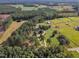 Aerial view of a home nestled in a wooded area with surrounding pastures and stables at 1100 Branch Chapel Church Rd, Selma, NC 27576