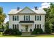 Two-story white farmhouse with black shutters, a front porch, and landscaping at 1502 Bahama Rd, Bahama, NC 27503
