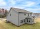 Back exterior view of a two-story gray home with a sunroom addition and grassy backyard at 1208 Randwick Valley Ct, Zebulon, NC 27597