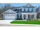 Two-story home with gray siding, stone accents, and a three-car garage at 591 Glenkirk Pl # 106, Garner, NC 27529