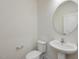 Clean, modern bathroom with pedestal sink and large circular mirror at 122 Whimbrel Ct, Lillington, NC 27546