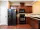 Kitchen with dark wood cabinets and black appliances at 202 Linden Park Ln, Cary, NC 27519