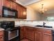 Kitchen with dark wood cabinets, black appliances, and double sink at 202 Linden Park Ln, Cary, NC 27519