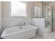 Relaxing bathroom featuring a soaking tub, marble tile, and a walk-in shower at 142 Lila Dr, Pittsboro, NC 27312