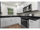 Modern kitchen with white cabinets, black countertops, and stainless steel appliances at 1006 Linwood Ave, Durham, NC 27701