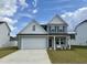 Two story home with a white and gray exterior, two car garage, and landscaping at 824 Putney Hill Rd, Zebulon, NC 27597