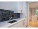 Modern laundry room with white cabinetry, a stylish backsplash, and a large utility sink at 23930 Cherry, Chapel Hill, NC 27517