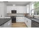Modern kitchen with white cabinets, a black countertop and a window at 2411 Adrift Rd, Fuquay Varina, NC 27526