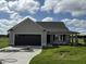 Tan house with dark brown garage door and landscaping at 95 Grace Ridge Ct, Benson, NC 27504