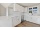 White kitchen with ample counter space, stainless steel appliances, and wood-look floors at 7814 Nc 27, Coats, NC 27521