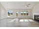 Spacious living room with wood-look floors, fireplace, ceiling fan, and large windows overlooking backyard at 7814 Nc 27, Coats, NC 27521