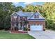 Two story home with brick and gray siding, two car garage, and landscaping at 319 River Knoll Dr, Clayton, NC 27527