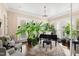 Sunlit music room features a piano, lush plants, and comfortable armchairs at 2117 Blue Haven Ct, Wake Forest, NC 27587