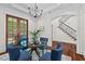 Bright dining room with glass table and four blue chairs, adjacent to staircase and French doors at 488 Colvard Farms Rd, Durham, NC 27713