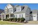Two-story house with gray siding, stone accents, and a three-car garage at 117 Hardy Oaks Way, Holly Springs, NC 27540
