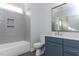 Modern bathroom with navy vanity, grey tile, and a bathtub at 370 Bellini Dr, Clayton, NC 27527