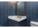 Stylish powder room with navy blue vanity, marble countertop, and geometric wallpaper at 370 Bellini Dr, Clayton, NC 27527