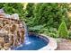 Rustic stone waterfall flowing into a circular pool at 110 Bywater Way, Chapel Hill, NC 27516