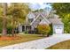 Two-story house with stone and gray siding, a driveway, and mature trees at 204 Harvest Ln, Pittsboro, NC 27312