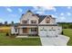 Two-story farmhouse exterior with gray siding, two-car garage, and landscaping at 5100 Grist Stone Way, Youngsville, NC 27596