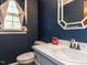 Small bathroom with white vanity, blue patterned wallpaper, and a window at 3701 Swann St, Raleigh, NC 27612