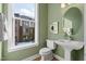 Stylish powder room with pedestal sink, oval mirror, and green walls at 1500 Village Hall Ln # 39, Wake Forest, NC 27587