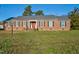 Brick ranch house with red door, landscaping, and a spacious yard at 1204 Breedlove Rd, Nashville, NC 27856