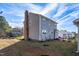 Side view of a two-story house with gray siding, brick chimney, and a small yard at 502 Lemontree Ct, Graham, NC 27253