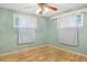 Bright bedroom featuring wood-look floors and two windows with curtains at 102 S 2Nd St, Micro, NC 27555