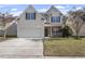 Two-story house with a light beige exterior, attached garage, and landscaping at 5230 Portside Ln, Raleigh, NC 27610