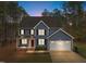 Night view of a two-story house with gray siding, white garage doors, and red front door at 5600 Thornburg Dr, Wake Forest, NC 27587