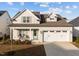 Two-story house with light beige siding, a two-car garage, and a front porch at 2913 Violet Way, Fuquay Varina, NC 27526