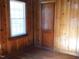 Simple bedroom with wood paneled walls, hardwood floors and a window at 477 Providence Rd, Roxboro, NC 27574