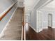 Carpeted staircase with wooden railing and hardwood floors at 237 Sweet Violet Dr, Holly Springs, NC 27540