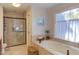 Spa-like bathroom with soaking tub, walk-in shower, and neutral tile at 1008 Oakgate Ct, Apex, NC 27502