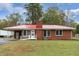 Brick ranch house with red metal roof, landscaped yard, and a long driveway at 604 Central Ave, Butner, NC 27509