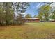 Back view of brick ranch house with red metal roof and a large backyard at 604 Central Ave, Butner, NC 27509