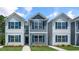 Three-unit townhome building with white and gray siding, landscaping, and walkways at 8656 Brixton Shay Dr, Raleigh, NC 27616