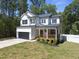 Two-story white farmhouse with black accents, wooden porch, and attached garage at 517 Shawnee Dr, Louisburg, NC 27549