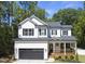 Two-story white farmhouse with black accents, wooden porch, and attached garage at 517 Shawnee Dr, Louisburg, NC 27549