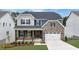 Two-story home with stone and shingle accents, a front porch, and a two-car garage at 3185 Armeria Dr, Apex, NC 27502