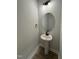 Elegant powder room with pedestal sink and circular mirror at 453 Edison Rail Ln, Knightdale, NC 27545