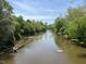 Serene riverfront view with lush greenery and natural rock formations at 4904 Caddis Bend, Raleigh, NC 27604