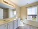 Bathroom with white vanity, toilet, and window overlooking the backyard at 1309 Silver Dr, Mebane, NC 27302