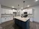 Modern kitchen with white cabinets, dark island, stainless steel appliances, and wood-look flooring at 136 S Mistflower St, Clayton, NC 27520