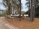 Front view of a single-wide mobile home with trees and a dirt driveway at 923 Sunny Ln, Raleigh, NC 27603